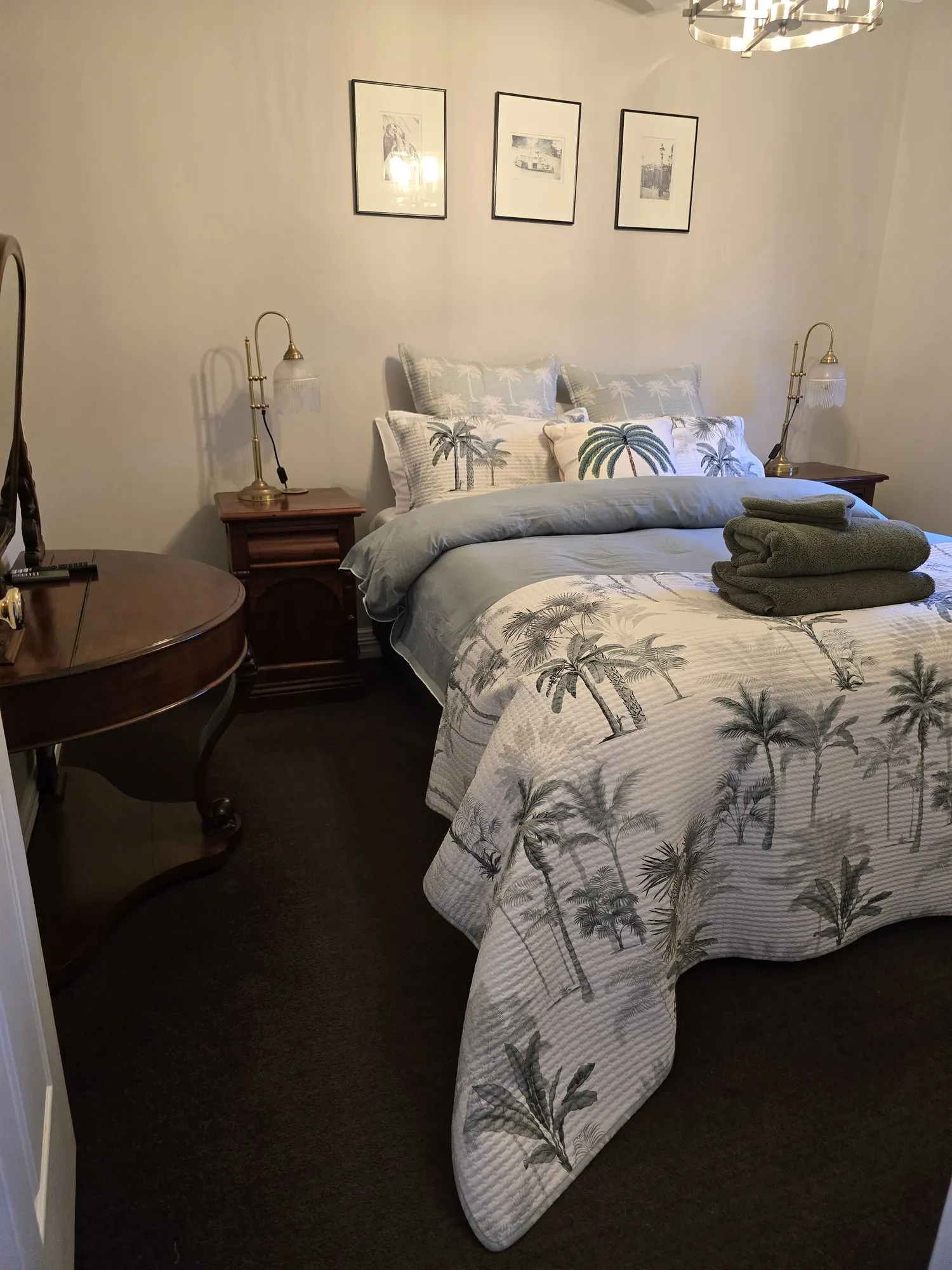 Philadelphia main bedroom with a palm-print quilt, brass lamps and three framed prints