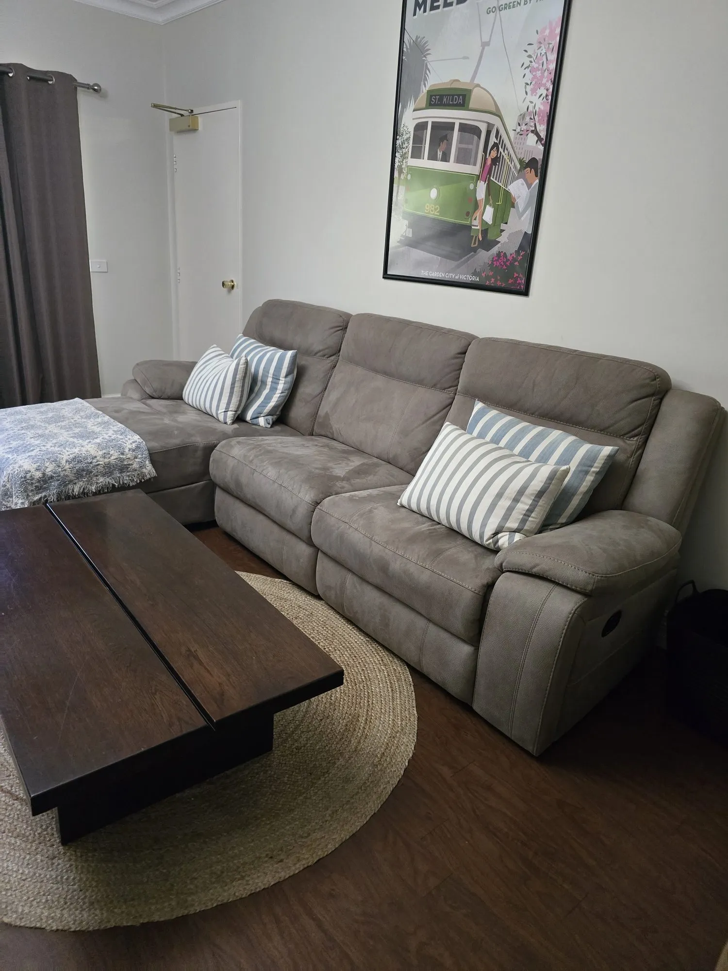 Henry Charles lounge with a grey modular sofa, timber coffee table and a vintage tram poster