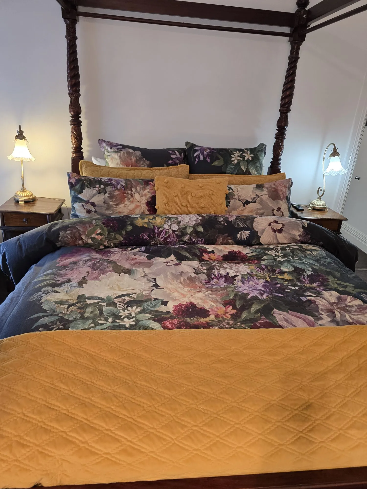 Floral bedding and gold cushions on the four-poster bed in the Adelaide Suite