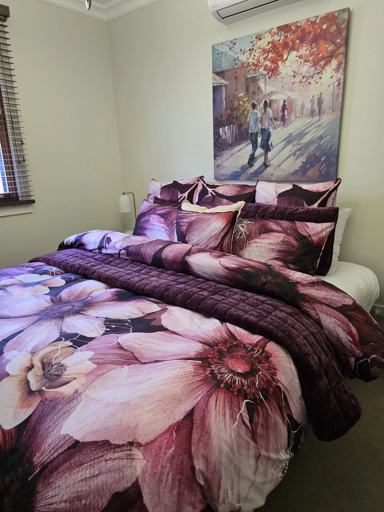 Second bedroom queen bed under a painting of a couple walking in autumn