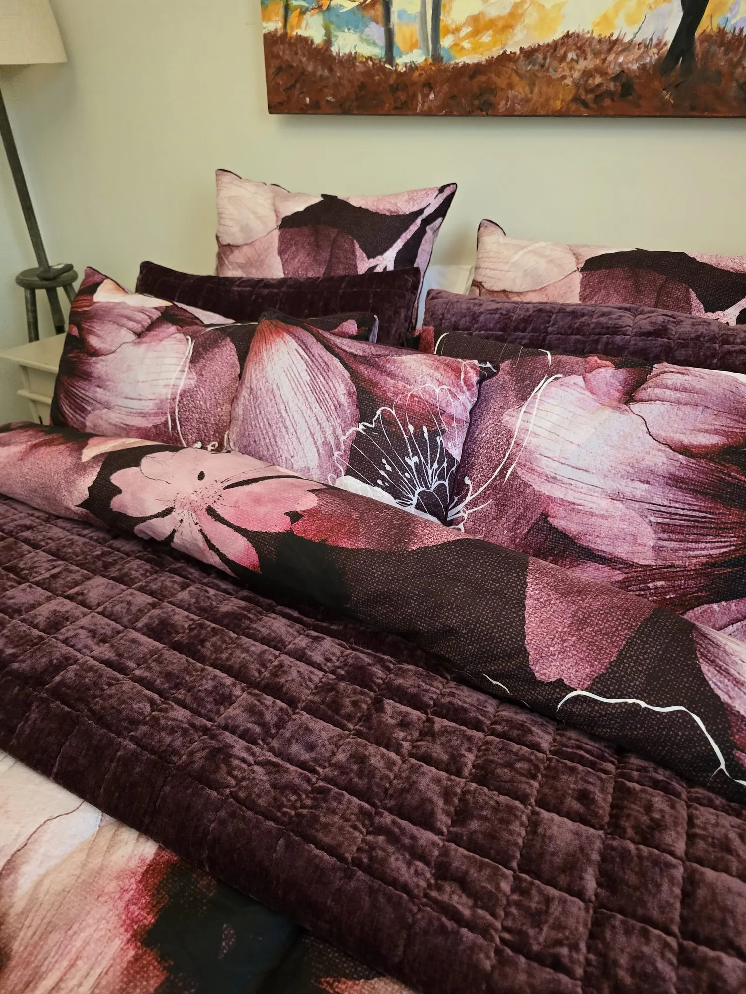 Plum velvet quilt and large floral cushions on the queen bed