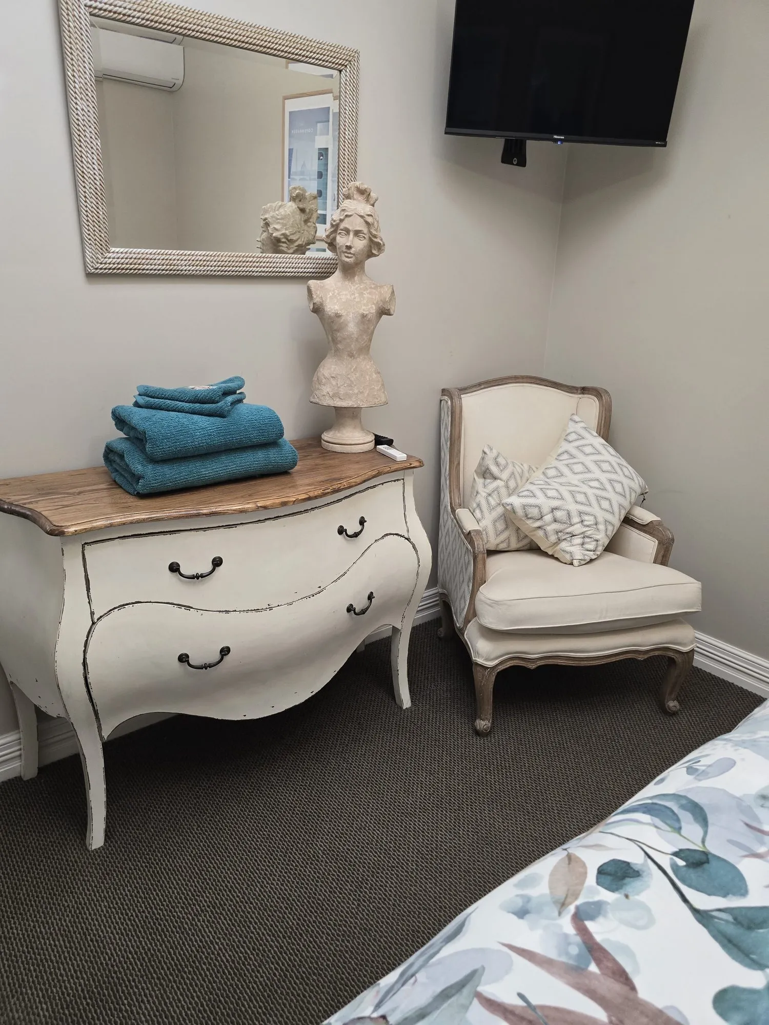 White French-style dresser with a classical bust, fresh towels and an armchair