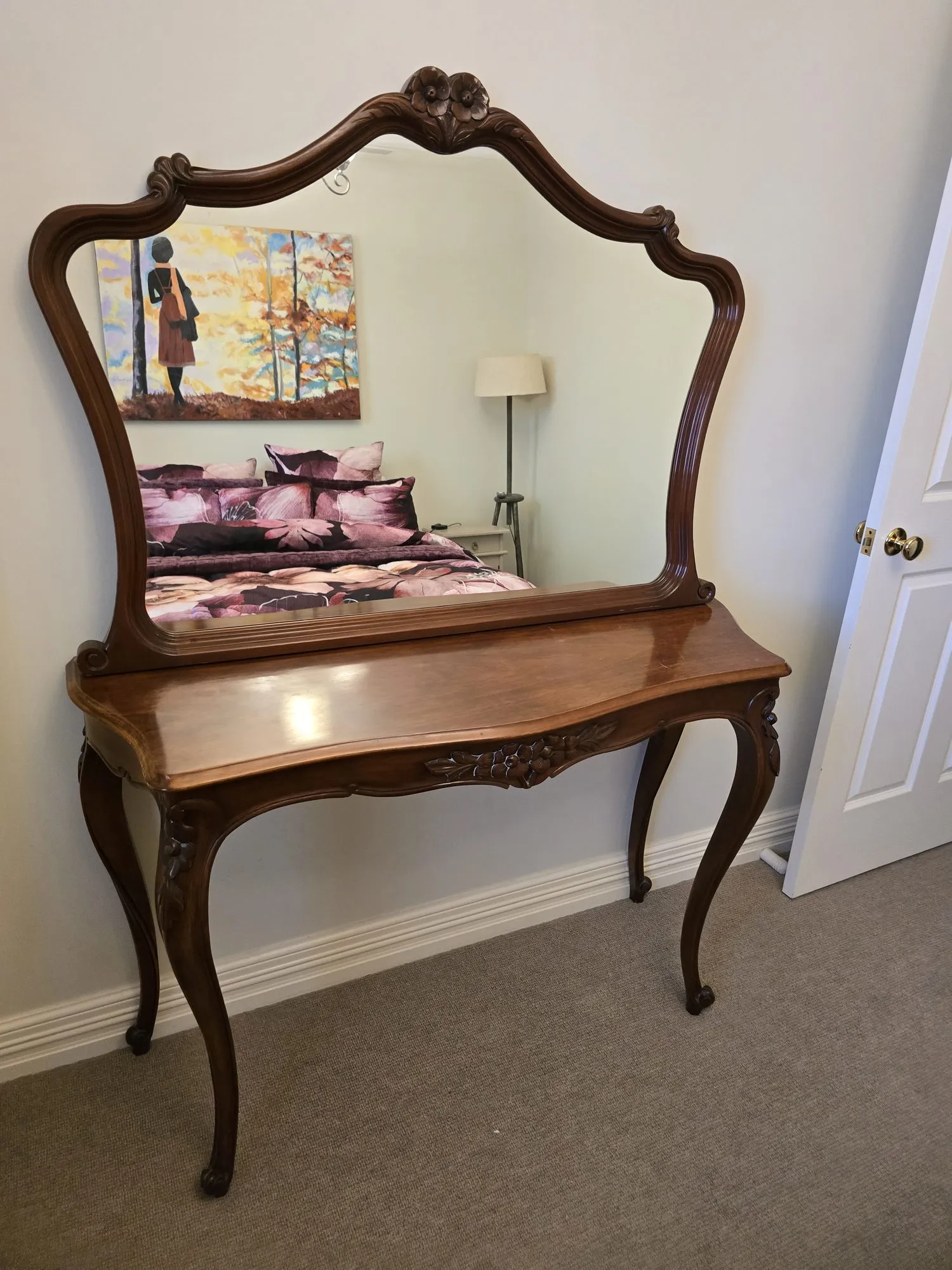 Carved antique dressing table whose mirror reflects the plum floral bed and autumn painting