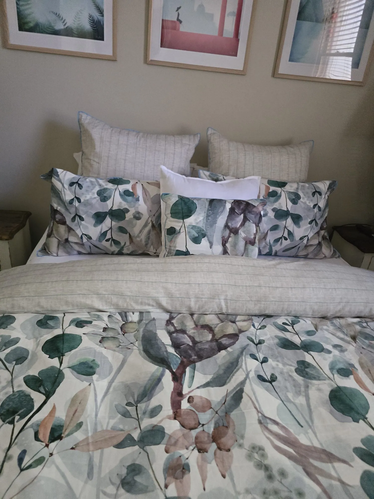 The main queen bed made up with layered cushions and a botanical quilt