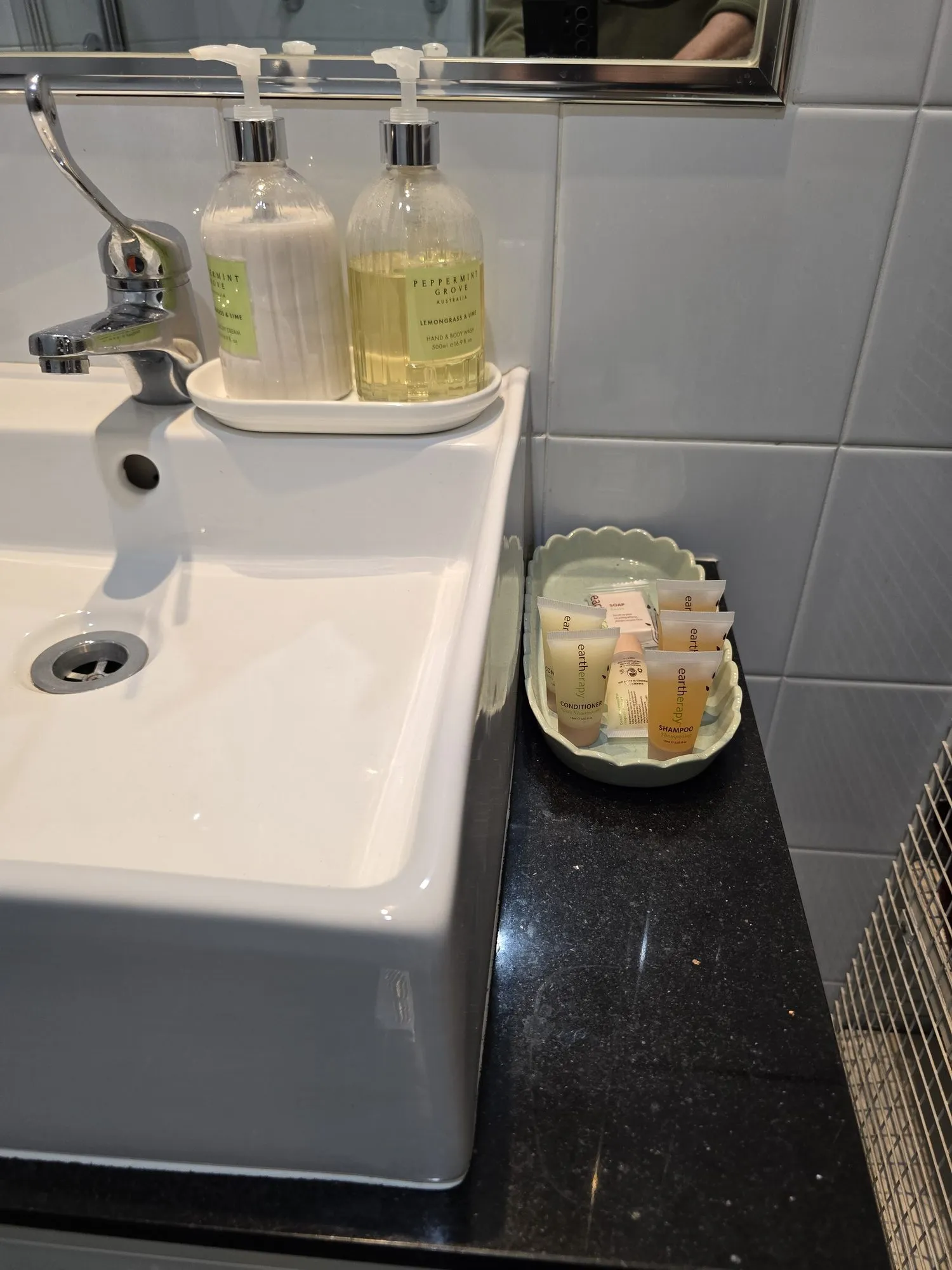 Bathroom vanity with a white basin, hand wash and guest toiletries